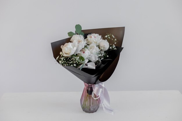 Bouquet with white peonies and eucalyptus in black packaging