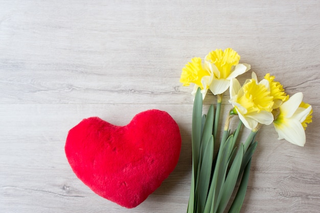 Bouquet of yellow daffodils and red heart toy, spring concept.