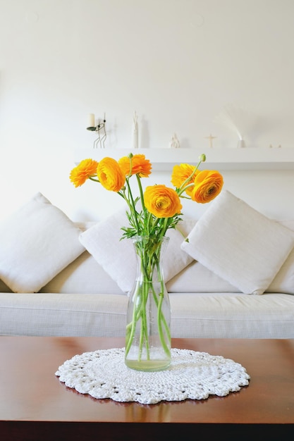 Bouquet of yellow flowers, ranunculus in a vase on a table in a cozy home on a sunny day in bedroom