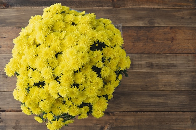 Bouquet of yellow flowers on wooden background. All Saints Day. Day of the dead. Copy space. Top view.