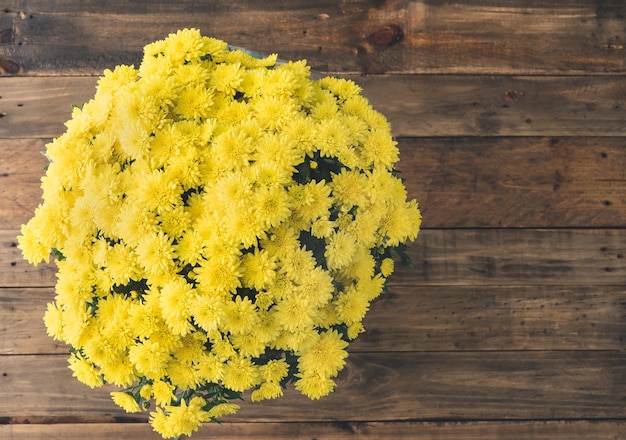 Bouquet of yellow flowers on a wooden background Top view Copy space