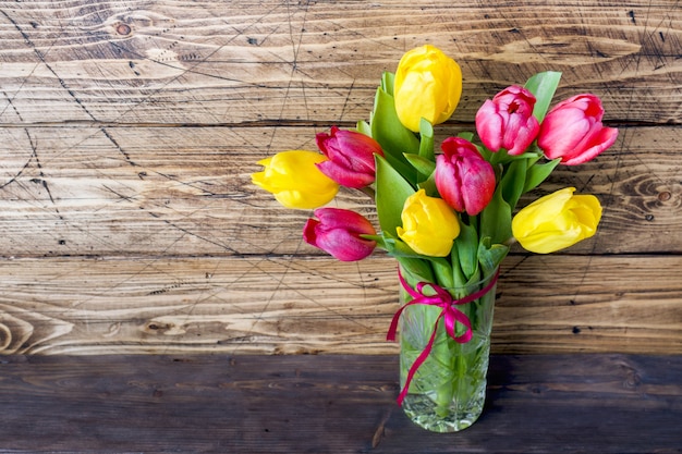 Bouquet of yellow and pink tulips on a wooden .