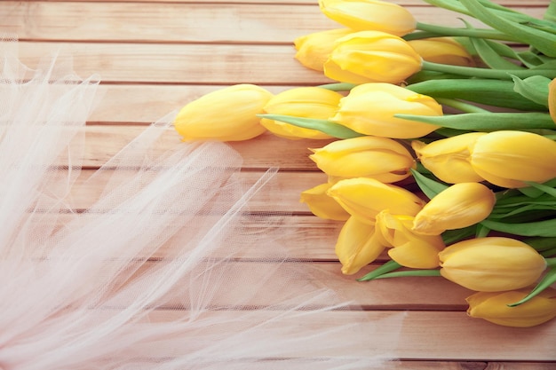 Bouquet of yellow tulips on wooden background