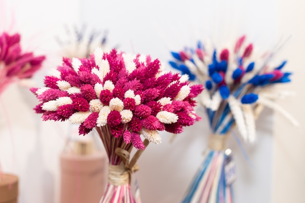 Bouquets of pink and blue wild dried stabilized flowers on the store. Floristics composition