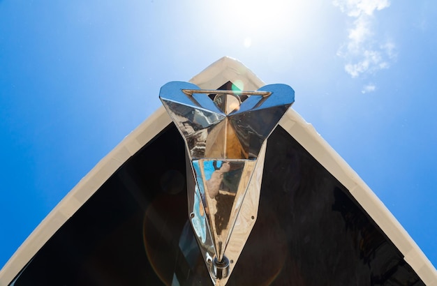 Bow of the yacht with anchor view from below against the background of the sky with sunlight