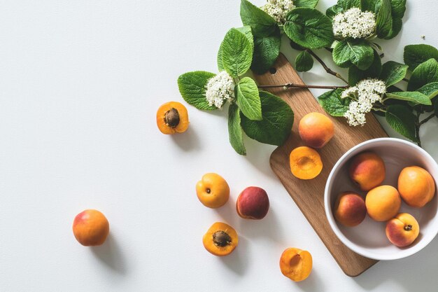 Photo a bowl of apricots with leaves and flowers on a table