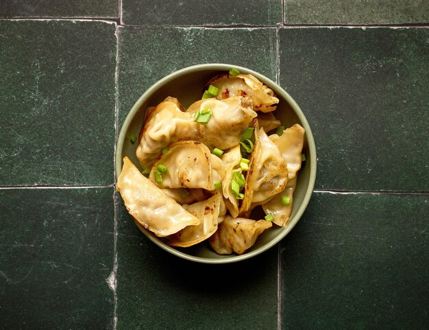 bowl of asian dumplings on green tiles background top view