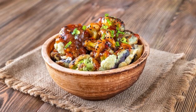 Bowl of Asian fried cauliflower on rustic background
