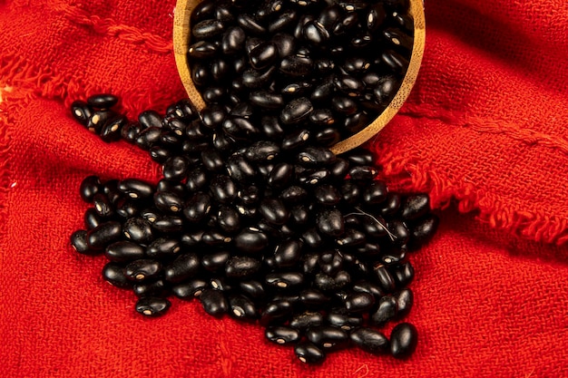 Bowl of black beans falling onto red cloth