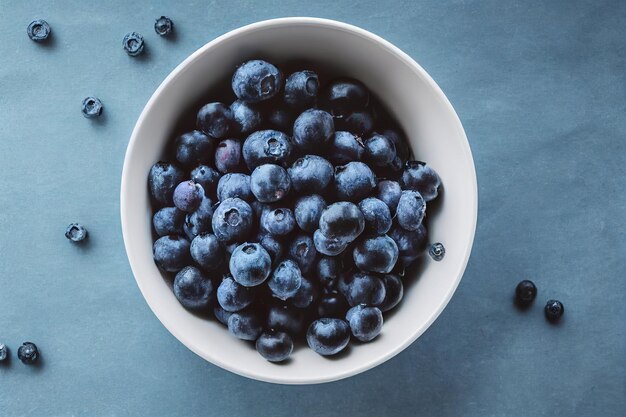 A bowl of blueberries sits on a blue table.