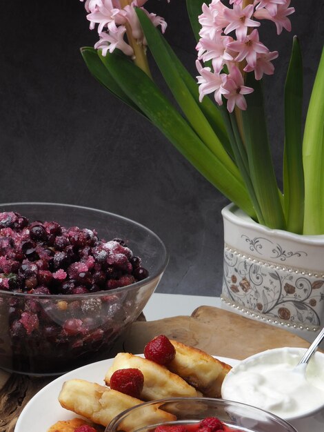 A bowl of blueberries sits next to a pink flower.