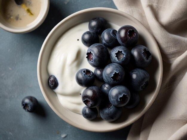 a bowl of blueberries with a bowl of yogurt on a table