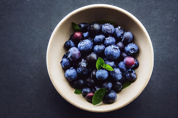 A bowl of blueberries with green leaves on a dark background