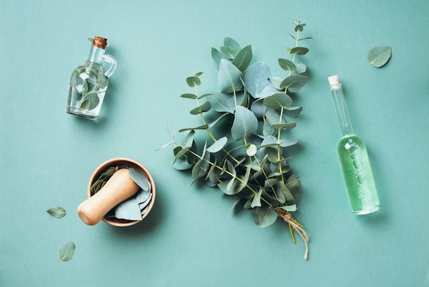 Photo bowl, bottles of eucalyptus essential oil, mortar, bunch of fresh eucalyptus branches