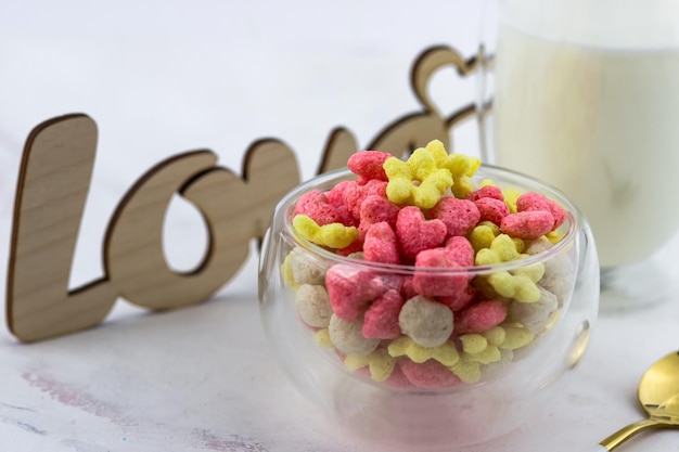 A bowl of breakfast cereal a glass of milk and a wooden love inscription on a white table Romantic breakfast