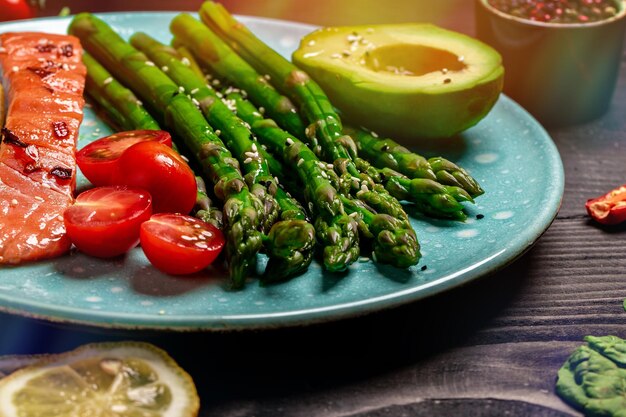 Bowl Buddha Baked salmon garnished with asparagus and tomatoes with herbs Food recipe background Close up