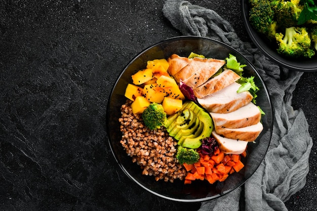 Bowl Buddha Buckwheat pumpkin chicken fillet avocado carrots On a black background Top view Free space for your text