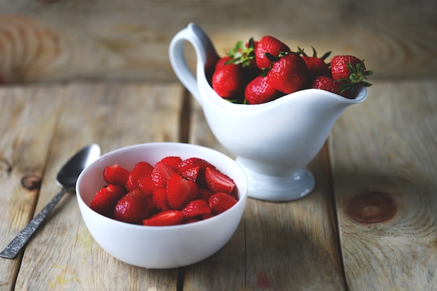 A bowl of chopped strawberries Gravy boat with strawberries