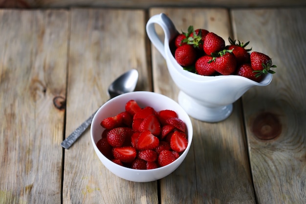 A bowl of chopped strawberries Gravy boat with strawberries