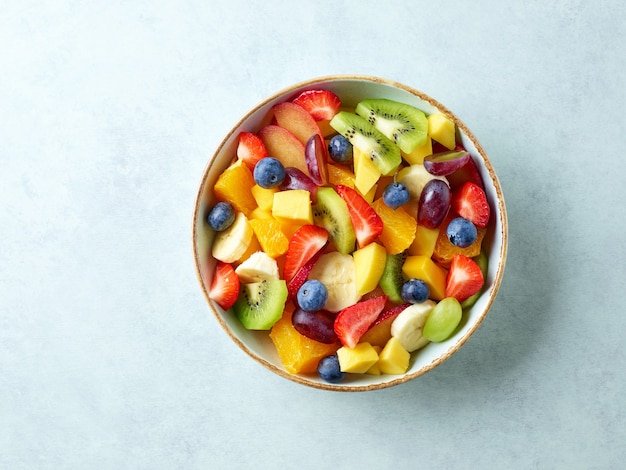 Bowl of colorful fresh fruit salad on kitchen table, top view