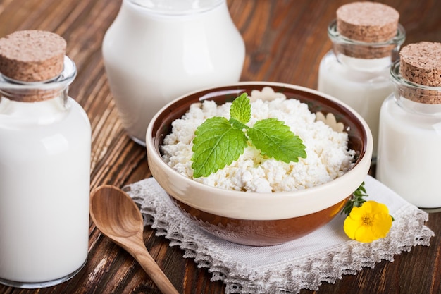 Bowl of cottage cheese and milk in glass container on wooden table