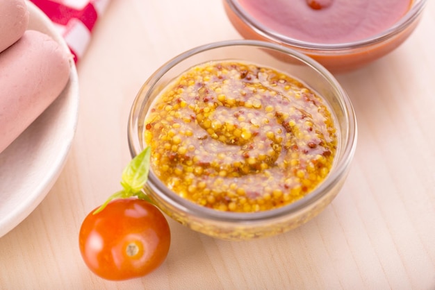 Bowl dijon mustard closeup and milk sausages on a background