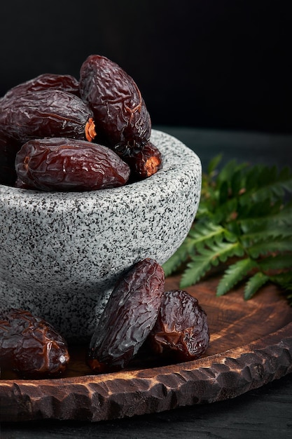 Bowl of dried dates on dark wooden background