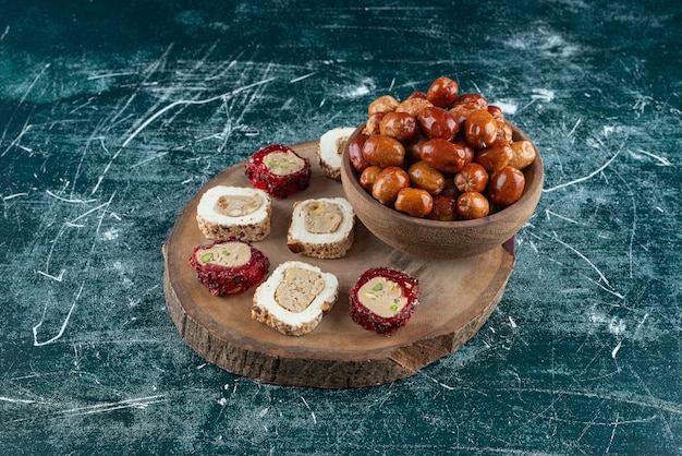 Bowl of dried dates and sweet delights on wood piece.