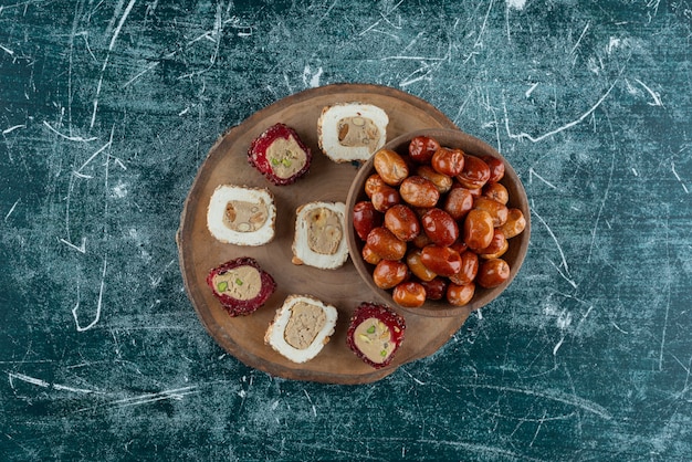 Bowl of dried dates and sweet delights on wood piece.