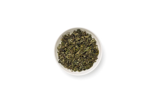 Bowl of dried green tea leaves on white background top view