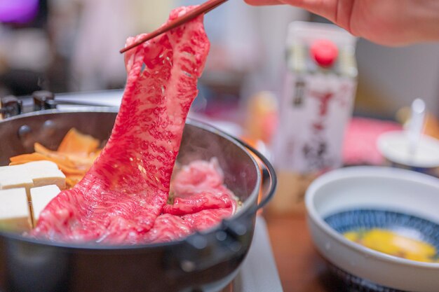 A bowl of food with a bottle of japanese hibachi on the table.