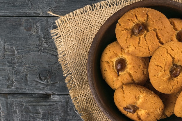 A bowl of fresh cookies on a black wooden table