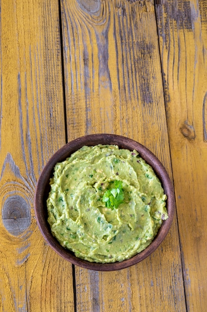 Bowl of fresh guacamole on rustic background