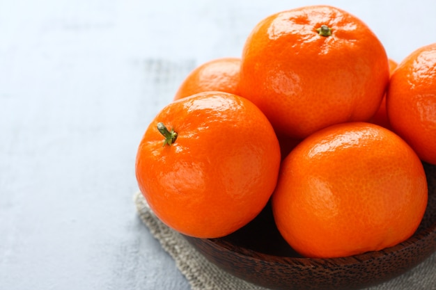 Bowl of fresh mandarins on gray background