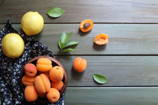 Bowl of fresh ripe apricots with leaves on a wooden table