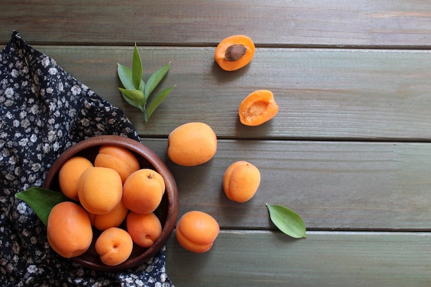 Bowl of fresh ripe apricots with leaves on a wooden table