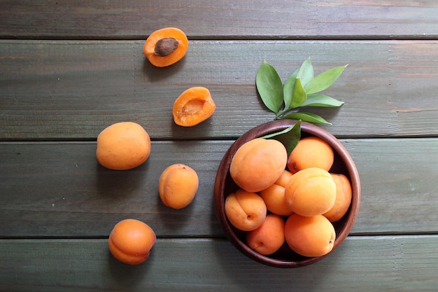 Bowl of fresh ripe apricots with leaves on a wooden table