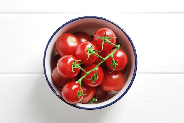 Bowl full of ripe fresh cherry tomatoes on wooden background