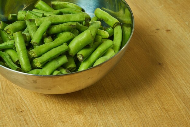 Photo a bowl of green beans sits on a wooden table.