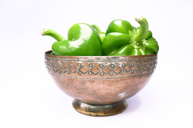 A bowl of green peppers sits on a white surface.