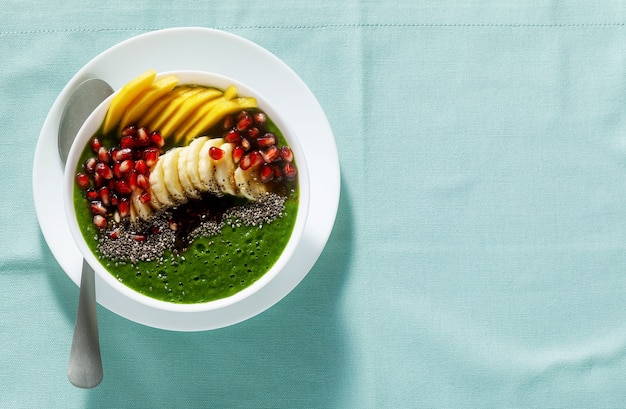 Bowl of green smoothie with sliced mango