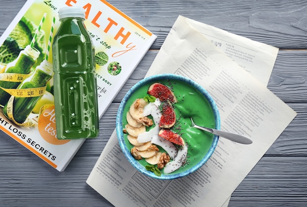 Bowl of green spirulina smoothie with fruits on table. Healthy vegan food concept