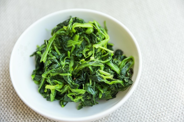 A bowl of green vegetables with the word spinach on it.