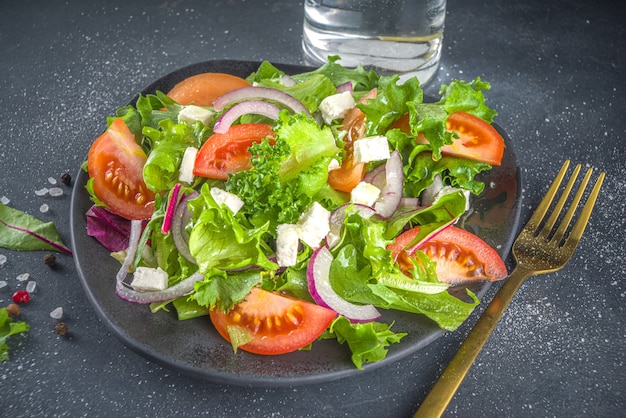 Photo bowl of healthy vegetable salad with various leaf salad, tomatoes, feta cheese, onions, olive oil