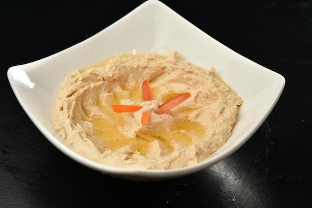 A bowl of hummus with carrots and celery on top.