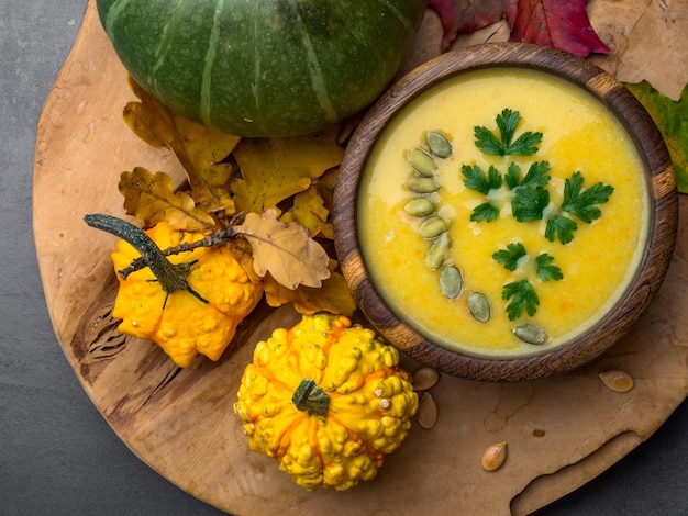 Bowl of lentil carrot and pumpkin soup with seeds parsley decorated with autumn foliage