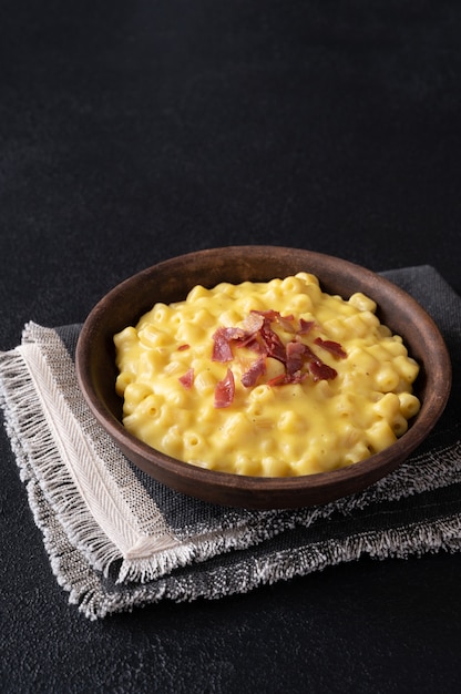 Bowl of macaroni and cheese with slices of fried bacon