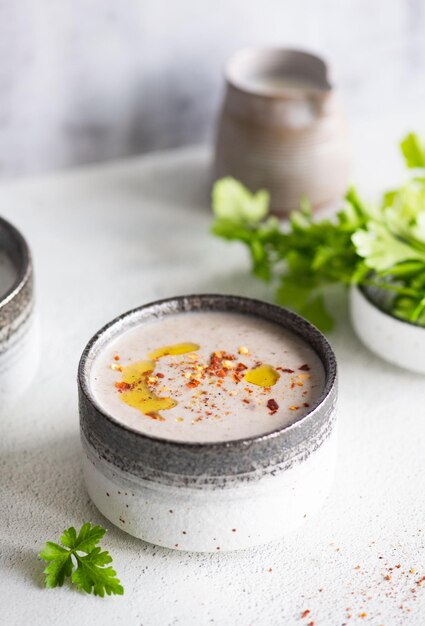 Photo a bowl of mango cream soup with a few other ingredients on a white table.