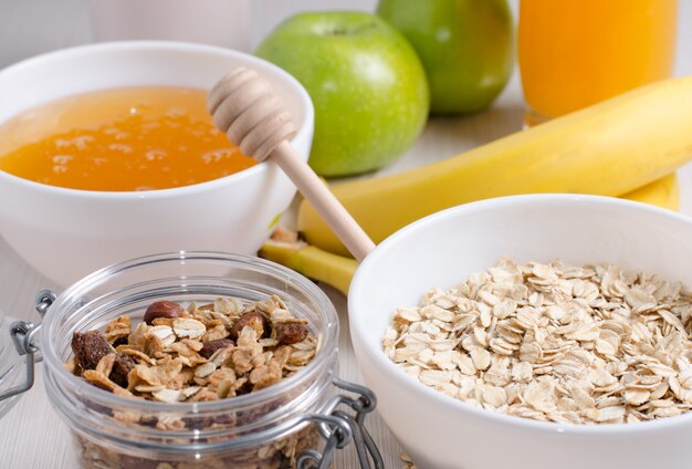 Bowl of oatmeal and raisins. Honey, bananas, green apples, nuts