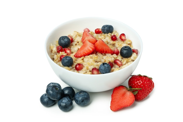 Bowl of oatmeal with tasty ingredients isolated on white background